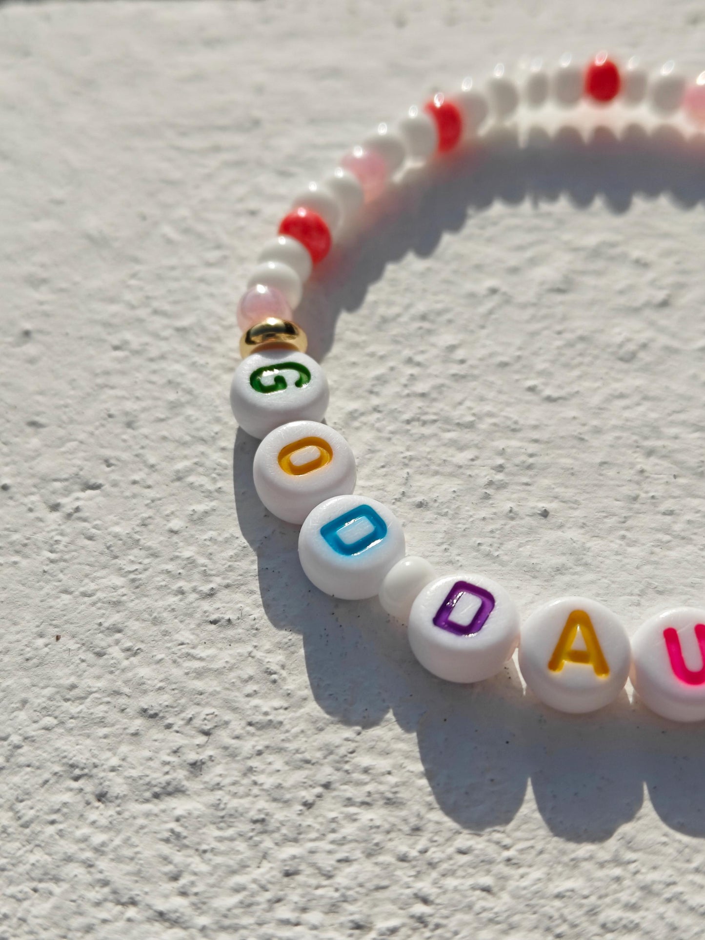 Colorful personalized name bead bracelet in pink white and gold with multicolored acrylic letter beads