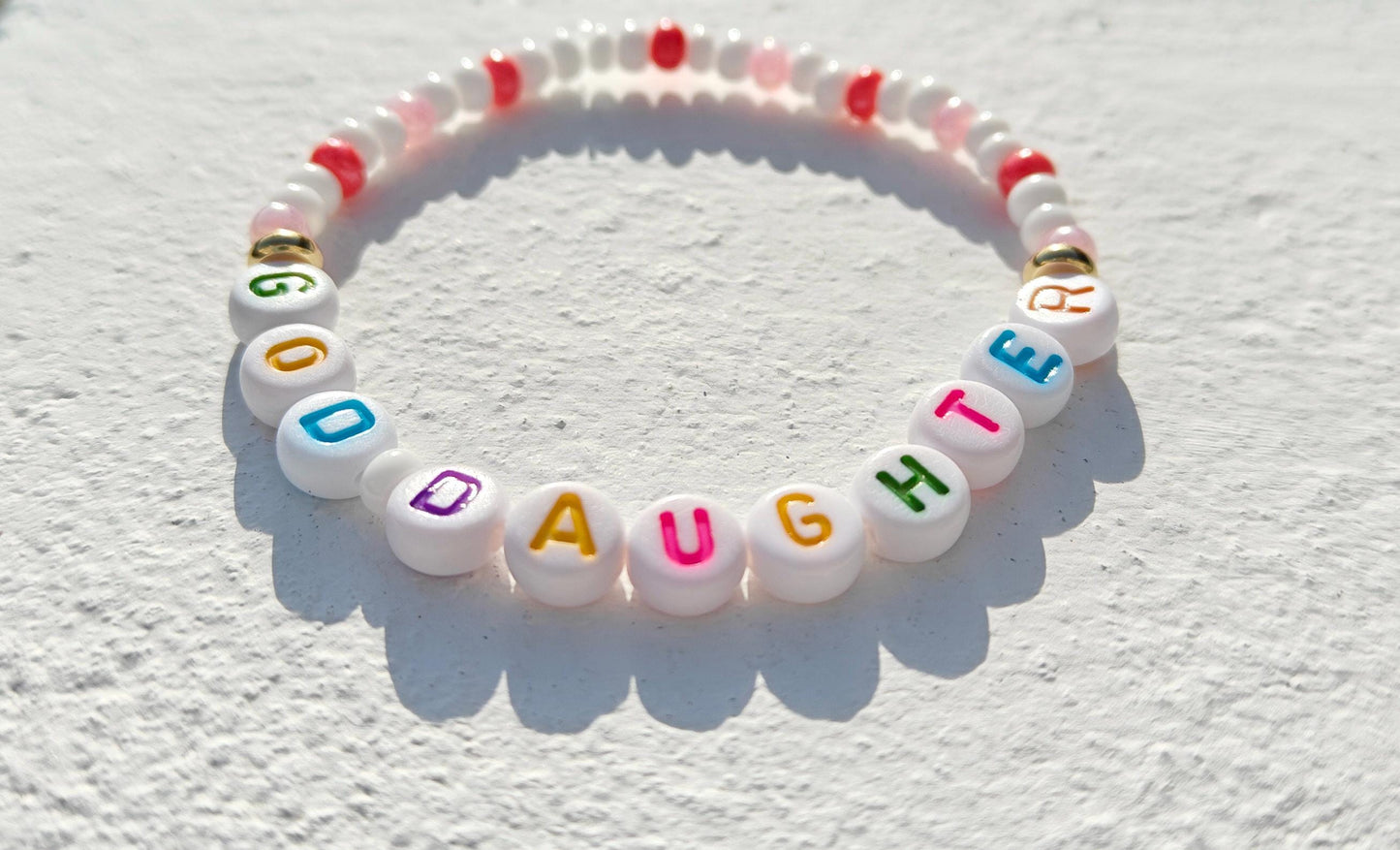 Colorful personalized name bead bracelet in pink white and gold with multicolored acrylic letter beads