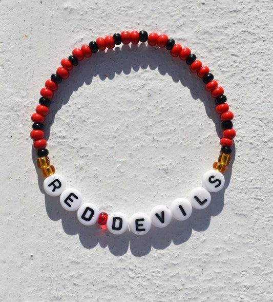 Red and black beaded bracelet with the words 'RED DEVILS' spelled out in white letters. The bracelet features small, round beads in alternating red and black colors, with gold spacer beads. White letter beads spell out the words 'RED DEVILS'.